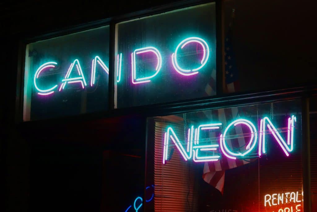 A neon sign in a shop window that reads, "Can Do Neon."