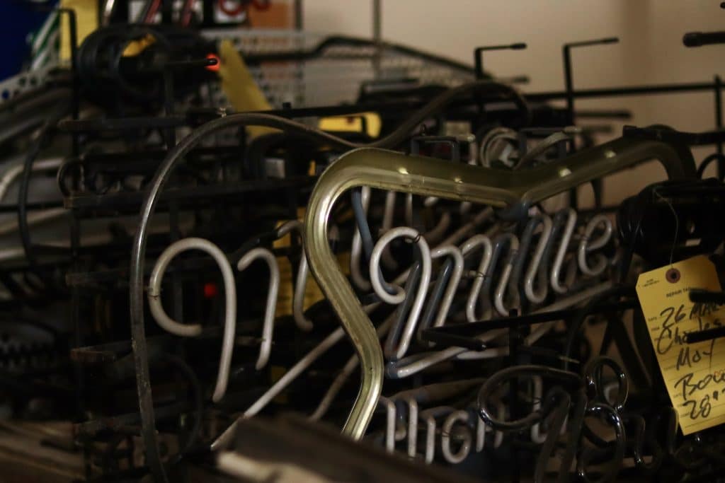 A group of dusty neon signs collected in the corner of a room. 